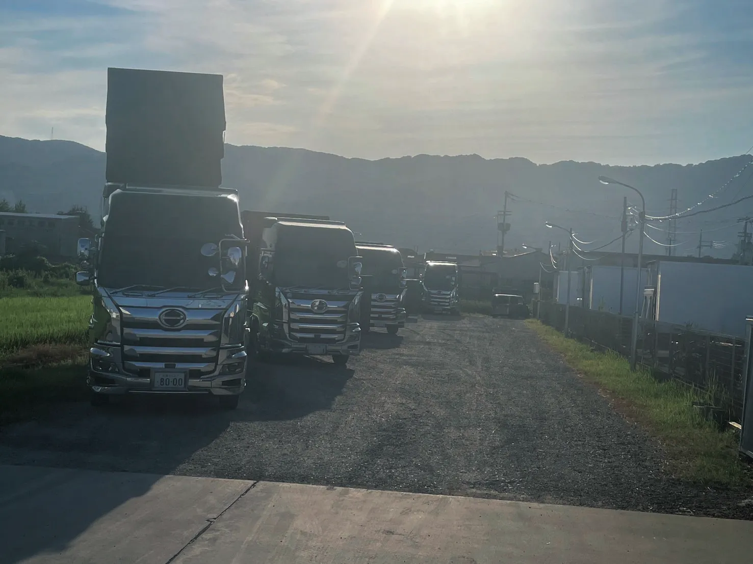 朝日を受けて並ぶ収集運搬用トラックの車列